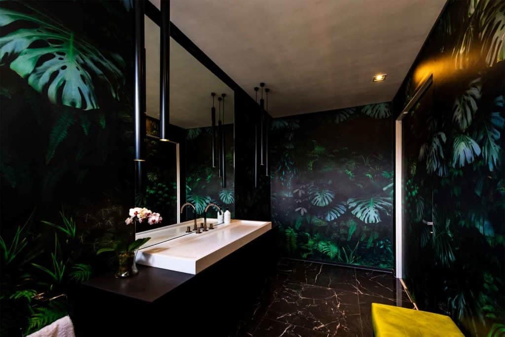 Dark tropical-themed wallpaper featuring large green leaves, with shades of emerald, forest, and jade greens on a deep ebony background.