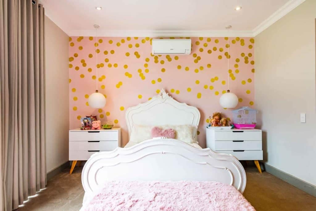 The focal point of the wallpaper is a playful pink background adorned with charming gold polka dots, enhancing the room's cozy ambiance and adding a touch of whimsy.