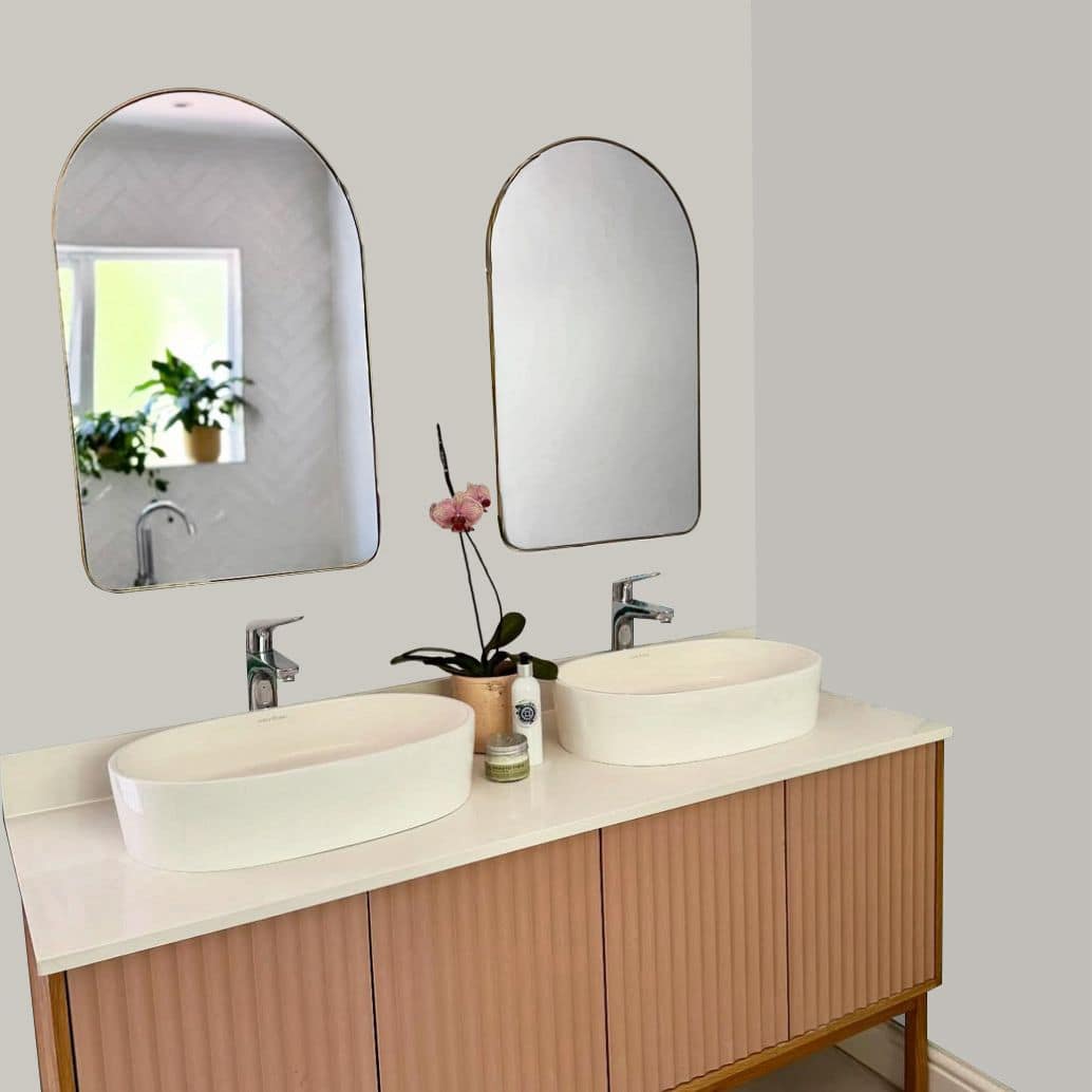 The bathroom features decorative wallpaper with bold, colorful floral patterns in shades of pink, green, and white. The distinctive wallpaper adds a vibrant backdrop behind the vanity and mirrors, easily highlighting its eye-catching design for search.