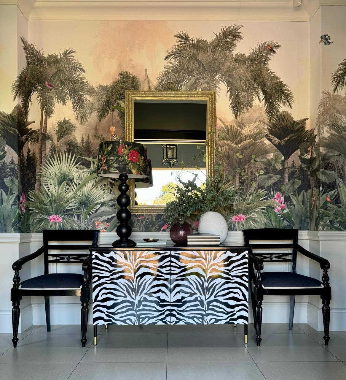 The wallpaper features a lush, tropical theme with vibrant green palm trees and plants. It's perfect for creating a natural, exotic ambiance. Key elements include detailed leaf patterns in varying shades of green and hints of earthy browns and soft yellows, giving it a lively yet sophisticated look.