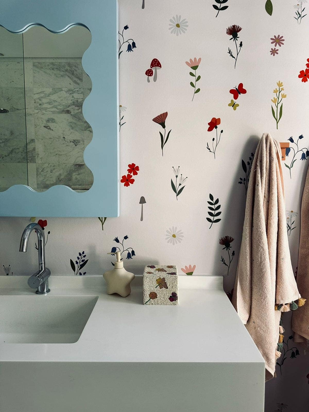 The wallpaper features whimsical floral and mushroom patterns in various bright colors, including shades of pink, yellow, green, and red. The motifs include flowers with intricate petals and playful mushrooms with spotted caps.