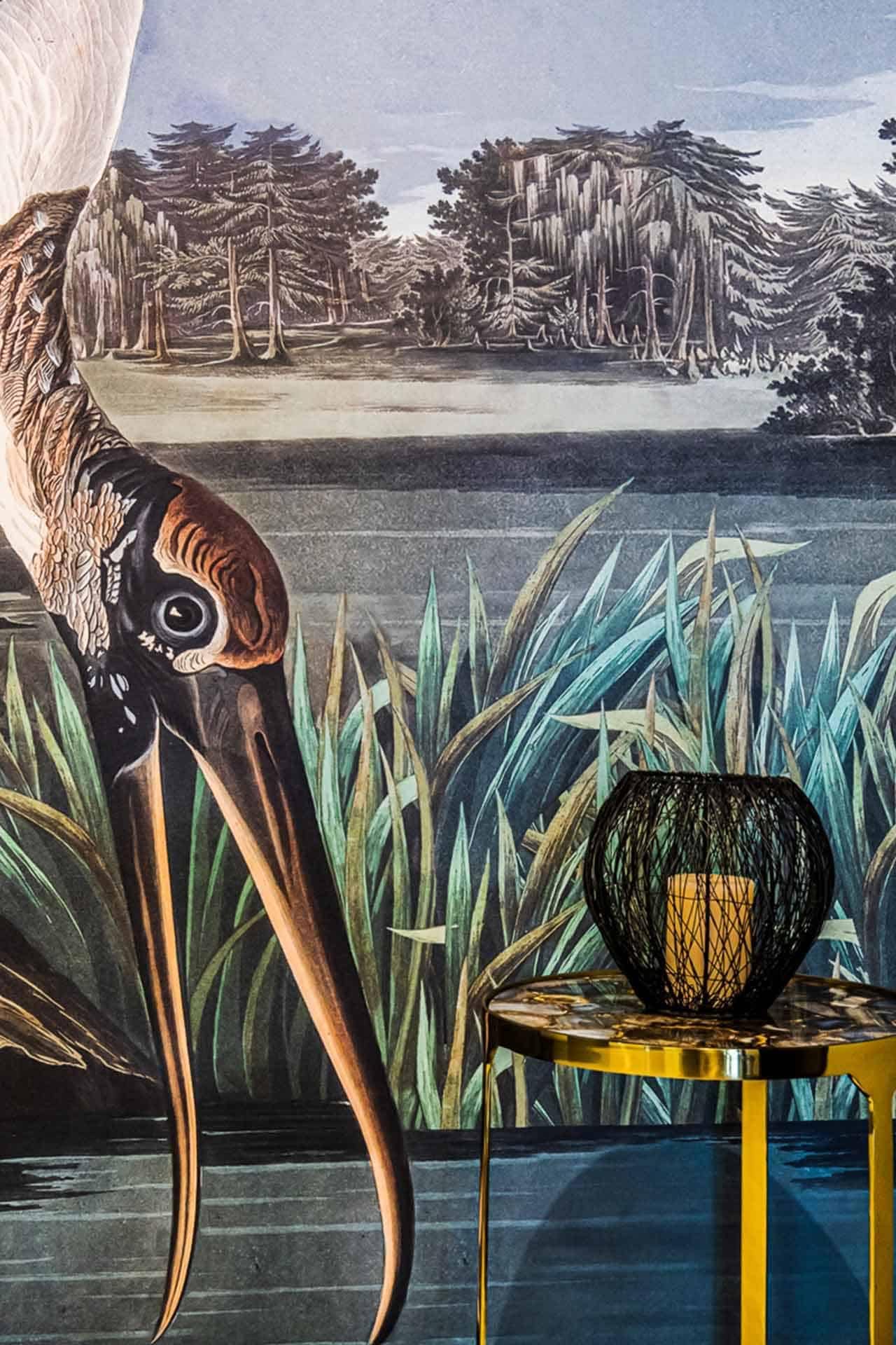 The wallpaper features a detailed close-up of a bird with a long beak and intricate feather patterns, rendered in vibrant hues. The serene wetland background includes tall grasses and trees, depicted in soothing shades of green and blue. Intricate details such as the bird's feathers and the landscape elements like grasses and trees are captured with precision, utilizing a rich color palette to enhance realism.