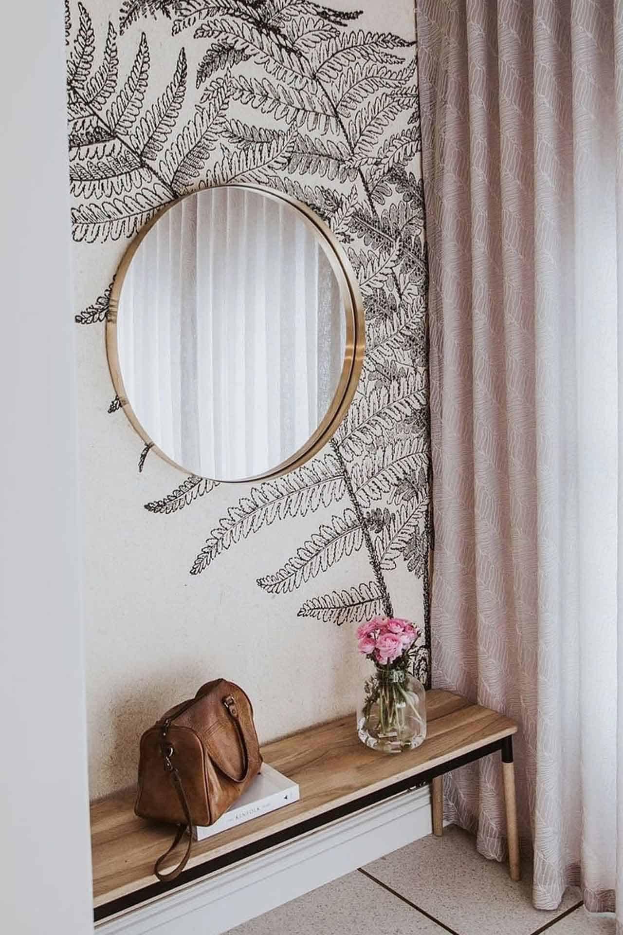 The wallpaper features black fern leaf designs, offering a stylish botanical aesthetic for a cozy entryway.