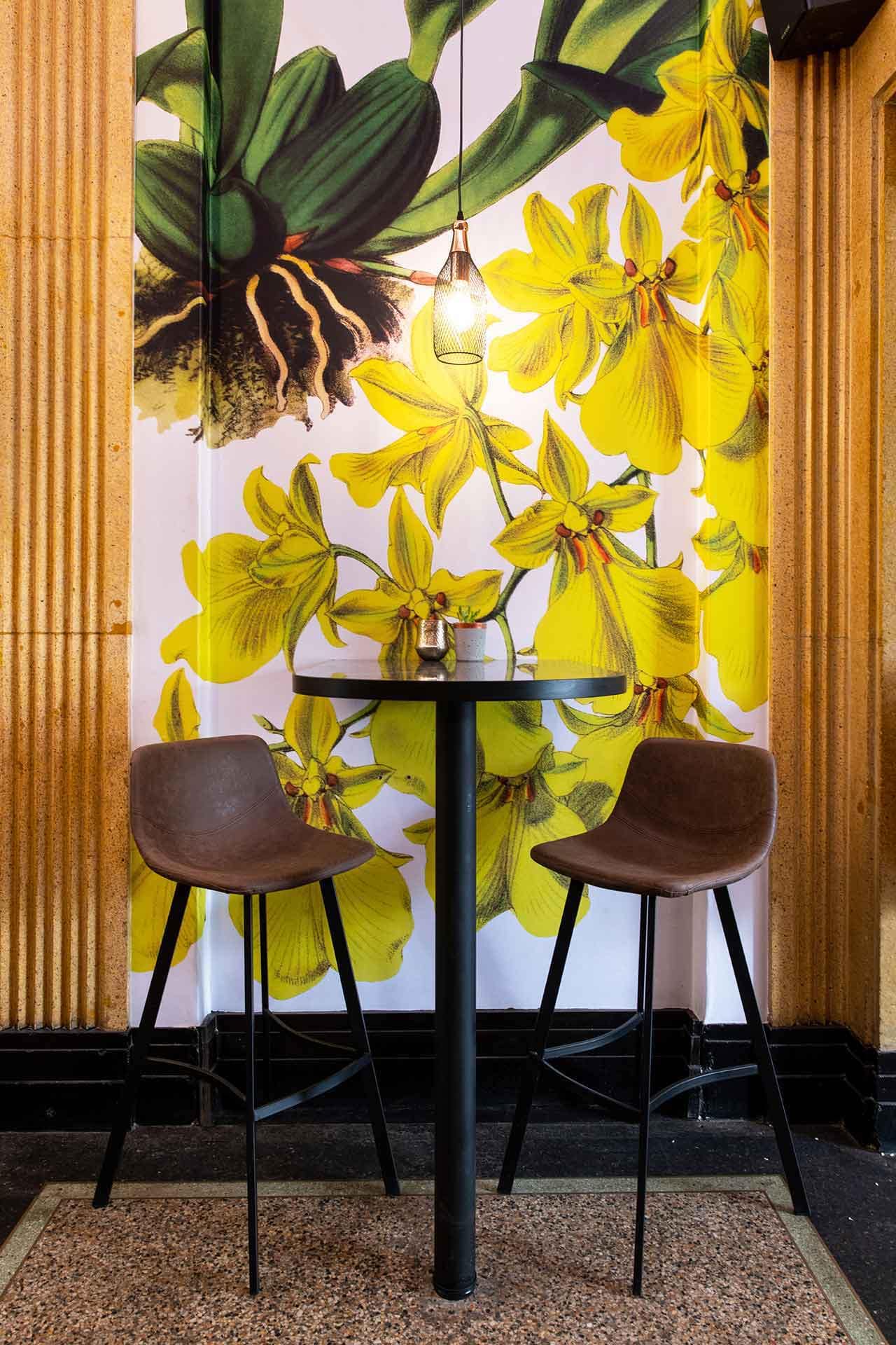 Vibrant yellow flower mural with intricate and colorful floral patterns. Hints of green stems and leaves, set against a detailed, textured backdrop.