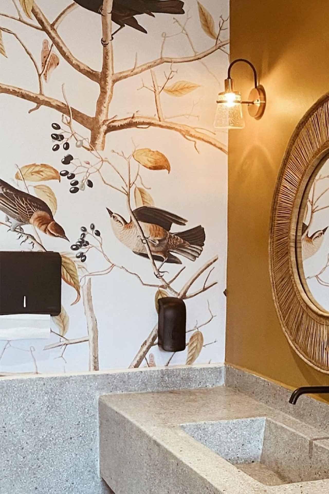 The bathroom wallpaper features a vibrant bird mural with detailed branches and ripe red berries, creating an eye-catching focal point. Key elements: birds, branches, berries. Predominant colors: rich reds of the berries and natural hues for the birds and branches.