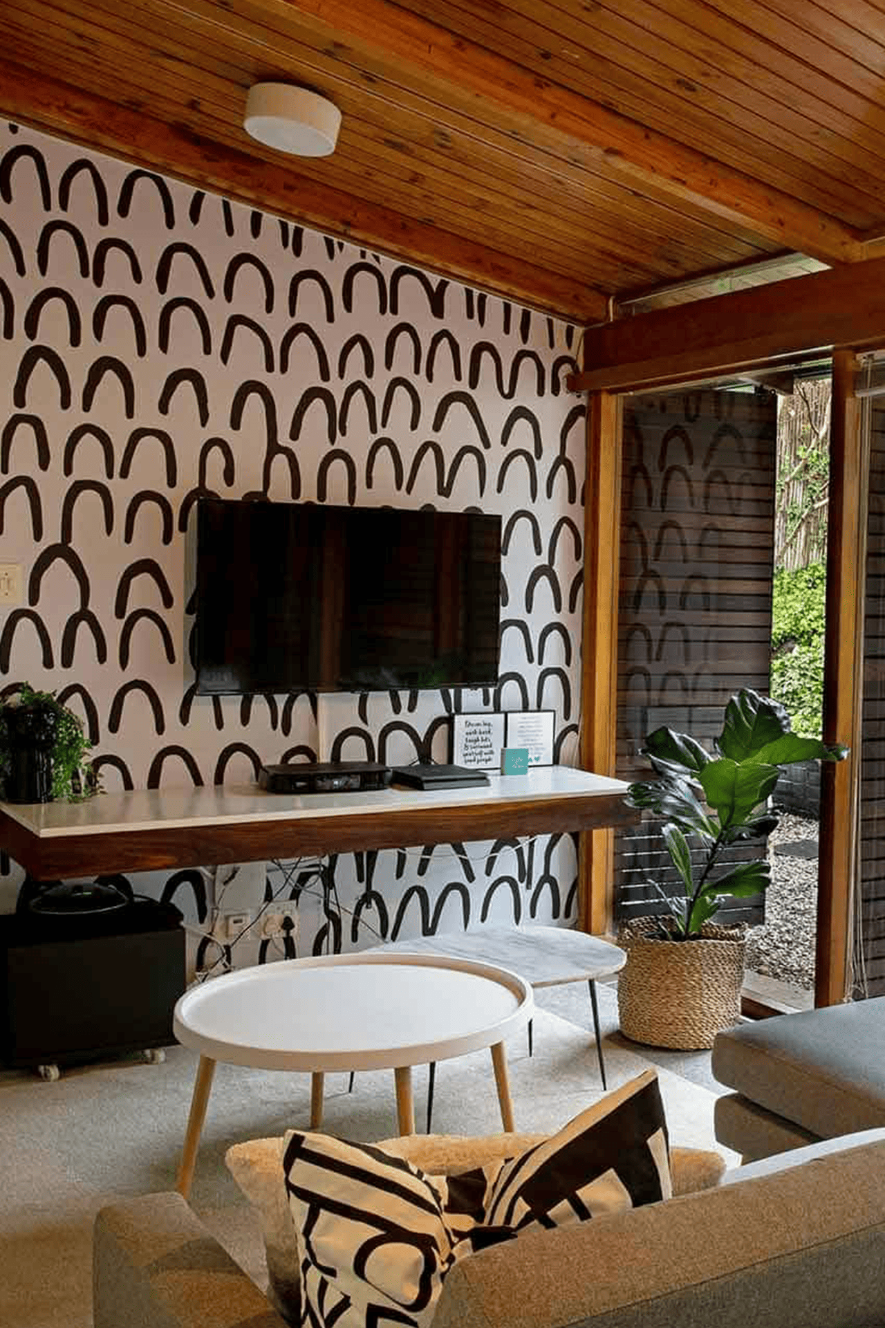 A modern living room features striking living room wallpaper with a patterned accent wall showcasing black arches on a white background.