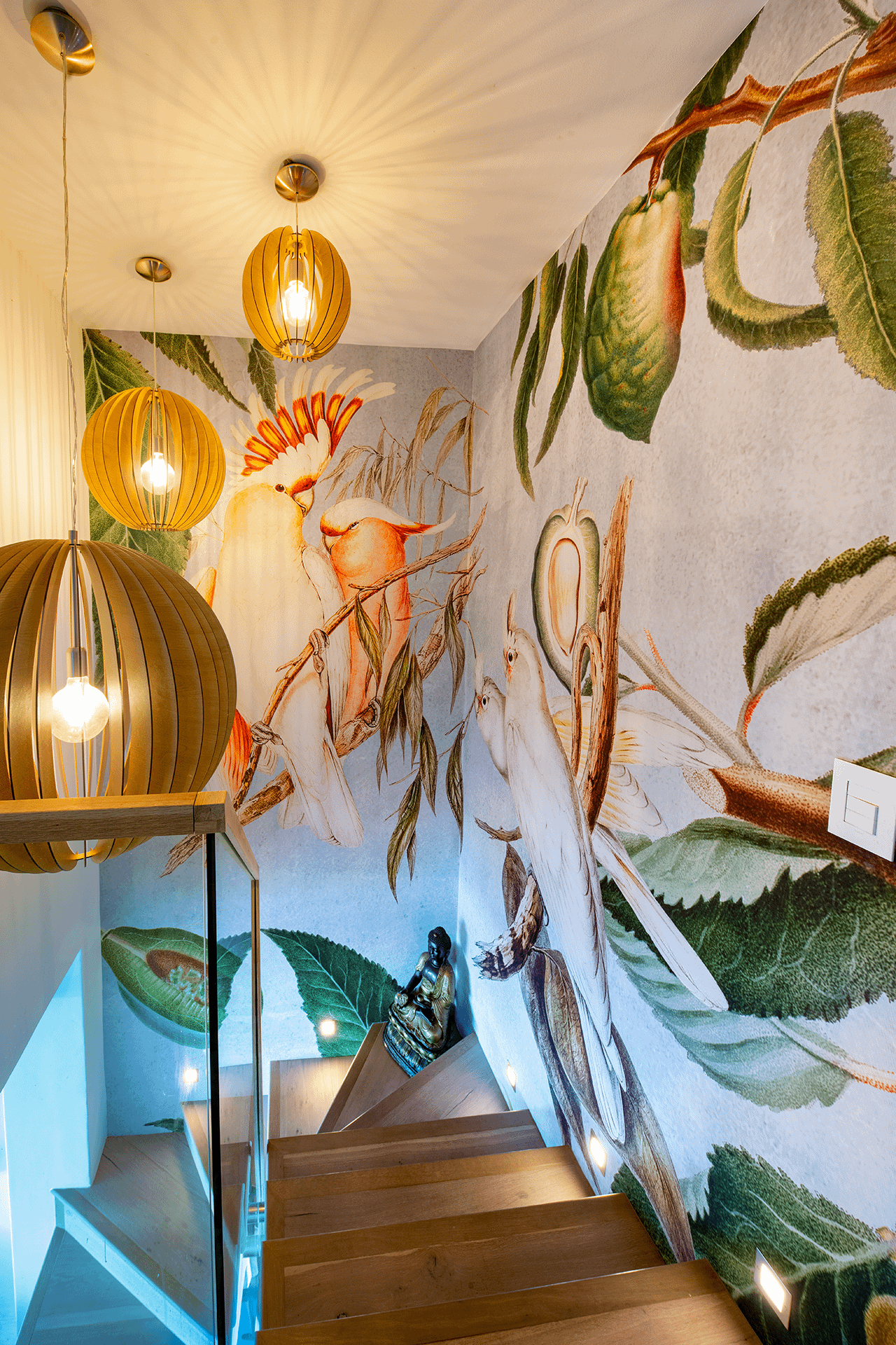 The living room wallpaper showcases a rich blend of vibrant tropical birds and lush foliage, featuring colors like emerald green, sunny yellow, vivid red, deep blue, and hints of orange.