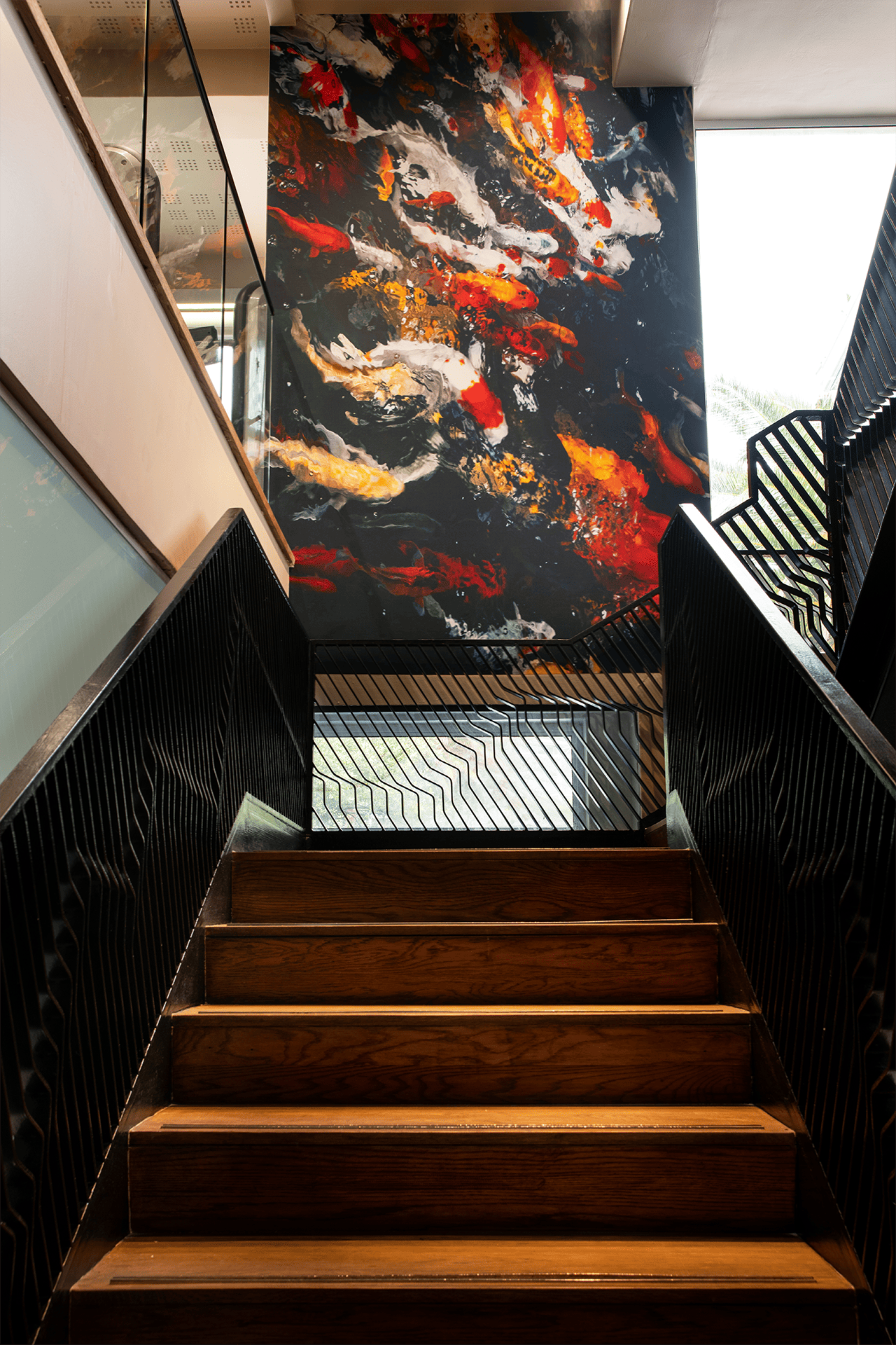 The vivid abstract painting features fiery red, orange, and white splashes against a dark background. These bold colors and dynamic elements make it a striking focal point at the staircase landing.