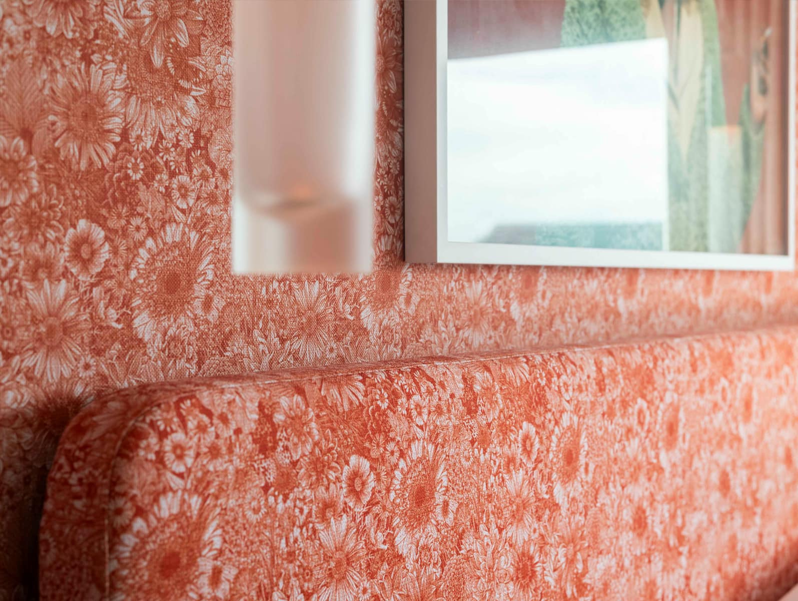 Close-up of orange floral-patterned wallpaper featuring vibrant orange flowers and leafy designs against a warm background, emphasizing the bold colors and intricate floral details.