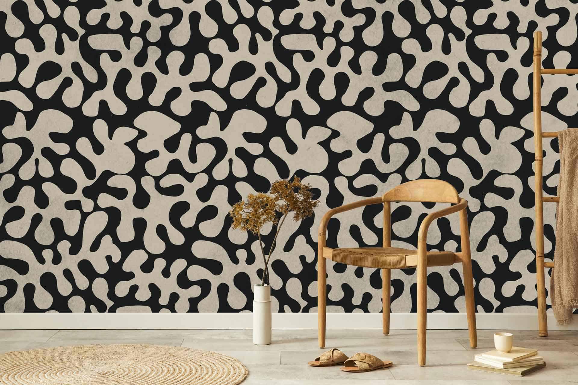 The wallpaper features a bold abstract black and tan pattern, reminiscent of historical art. It includes sharp lines, intricate curves, and dynamic shapes. The primary colors in the wallpaper are deep black and rich tan, creating a striking contrast that draws attention. The pattern is elaborate yet balanced, making it both eye-catching and harmonious within the room's decor.