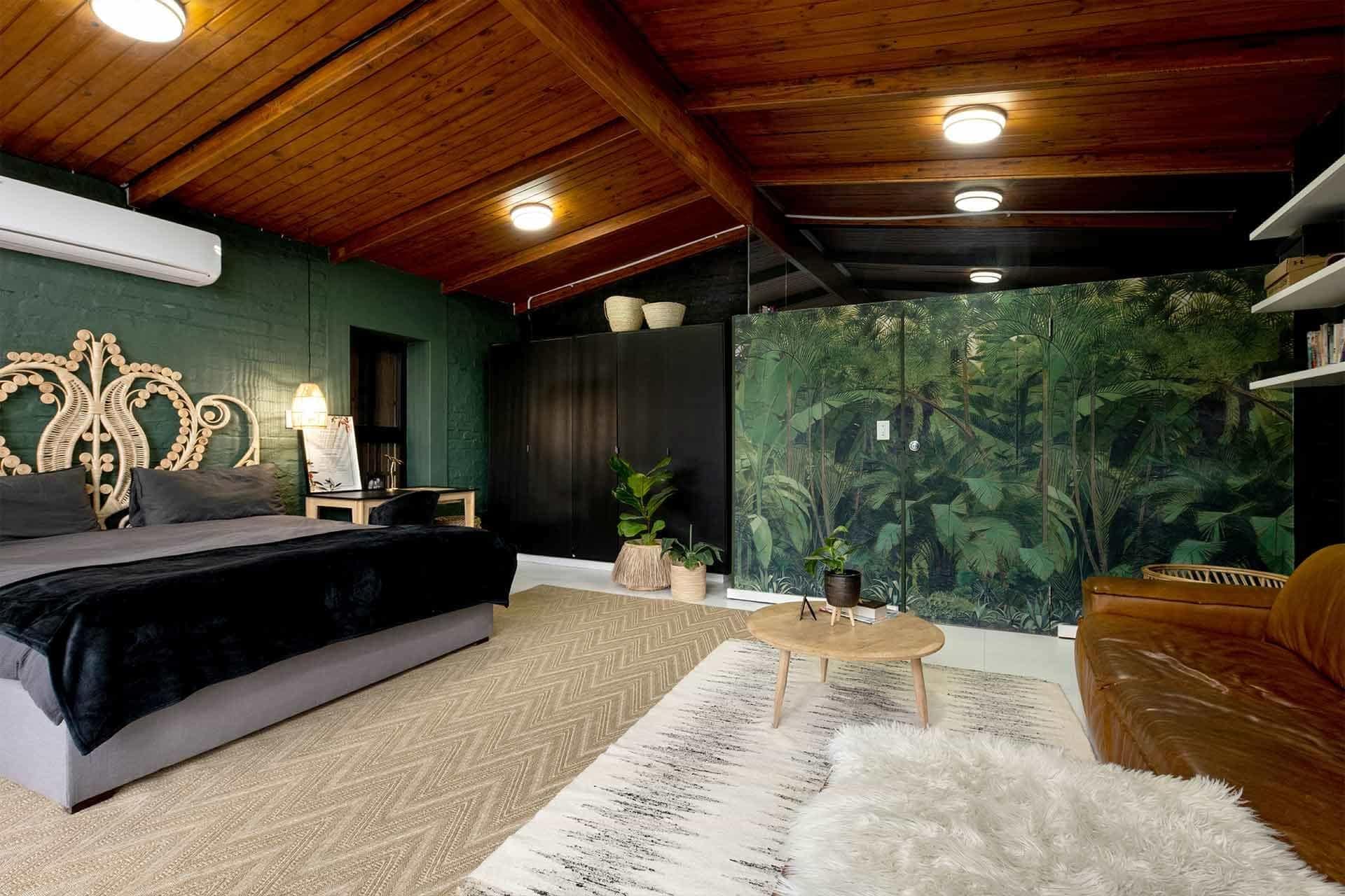 The wallpaper in the cozy bedroom features a green leafy mural, adding natural and vibrant elements to the room. The design emphasizes lush greenery with intricate leaf patterns.