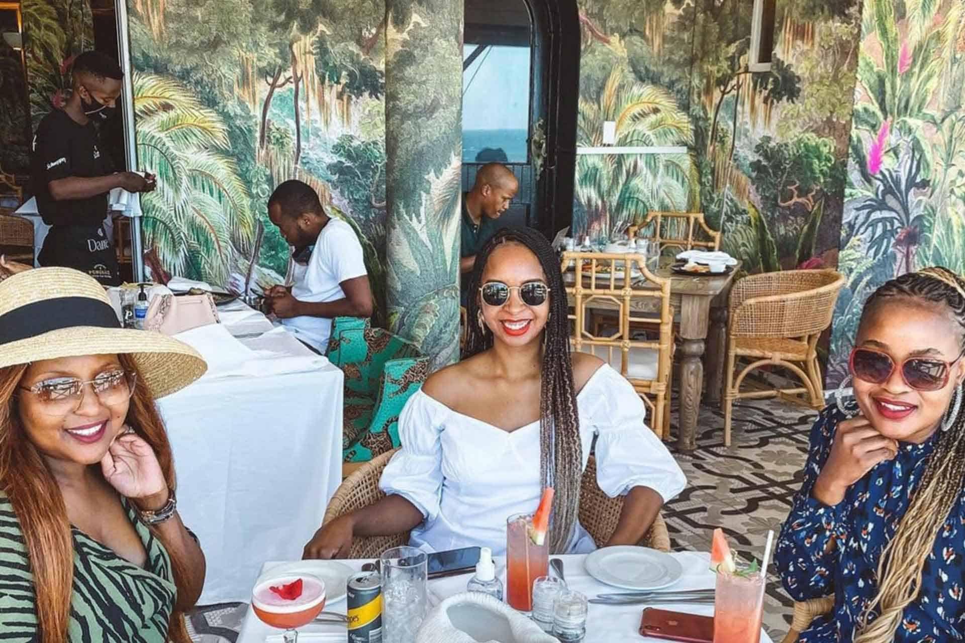 Tropical-themed wallpaper featuring lush green palm leaves, vibrant hibiscus flowers in pinks and reds, golden pineapples, and colorful exotic birds like parrots and toucans. The background of the wallpaper is a soothing aqua blue with splashes of coral tones. Small accents include banana leaves and coconuts for added detail. Perfect for a vibrant portfolio setting.