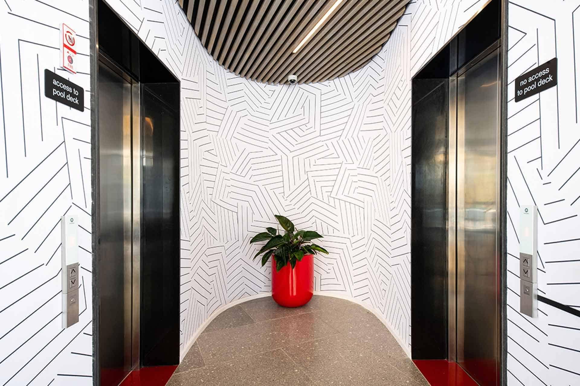 Contemporary elevator lobby wallpaper features a geometric pattern with bold black and white elements, creating a striking design. Key components: geometric shapes, monochrome (black and white), modern aesthetics.