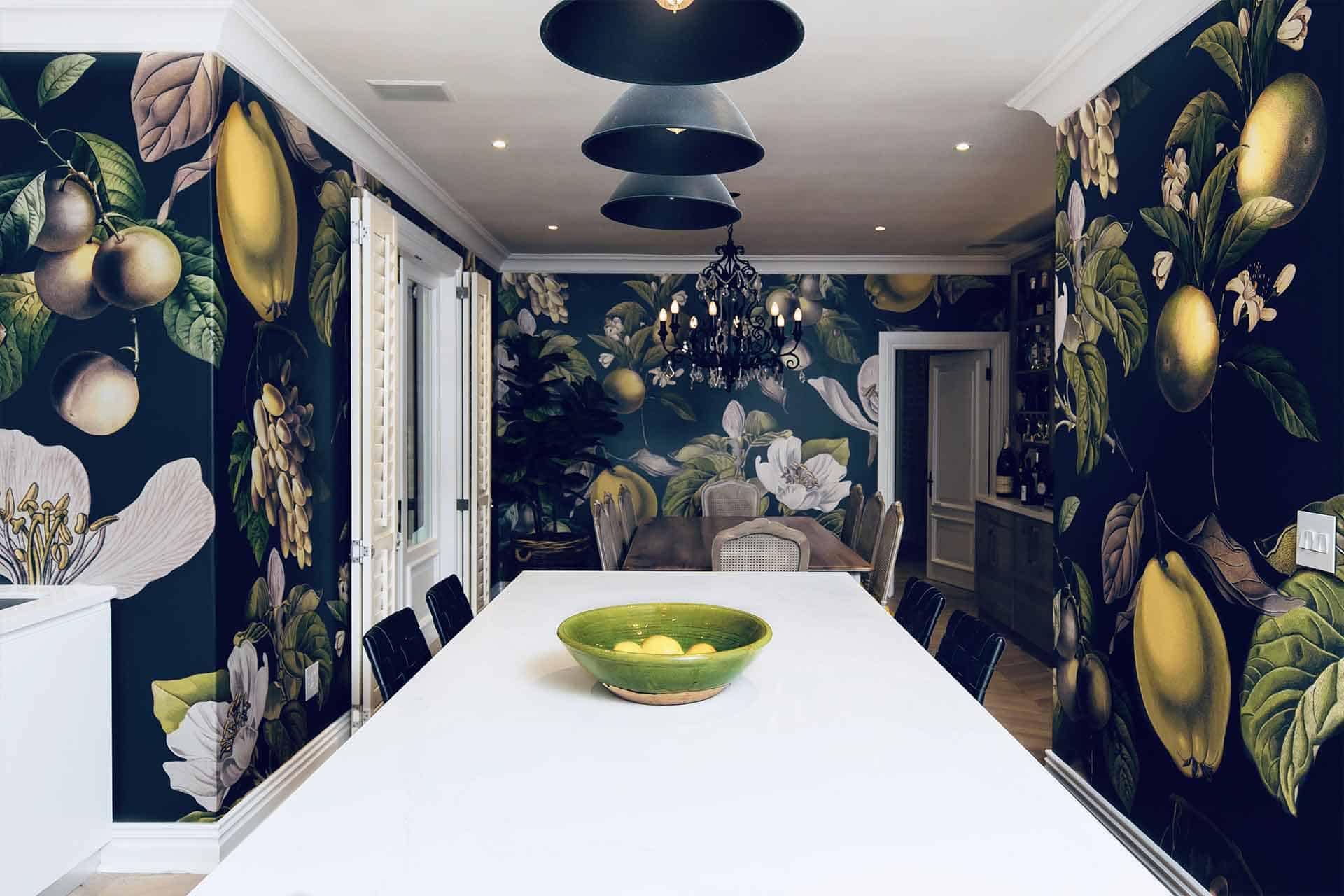 Our modern dining room features striking dark-toned wallpaper with floral and fruit themes. The wallpaper showcases intricate designs of flowers and fruits, incorporating deep greens, rich purples, and subtle hints of yellow.