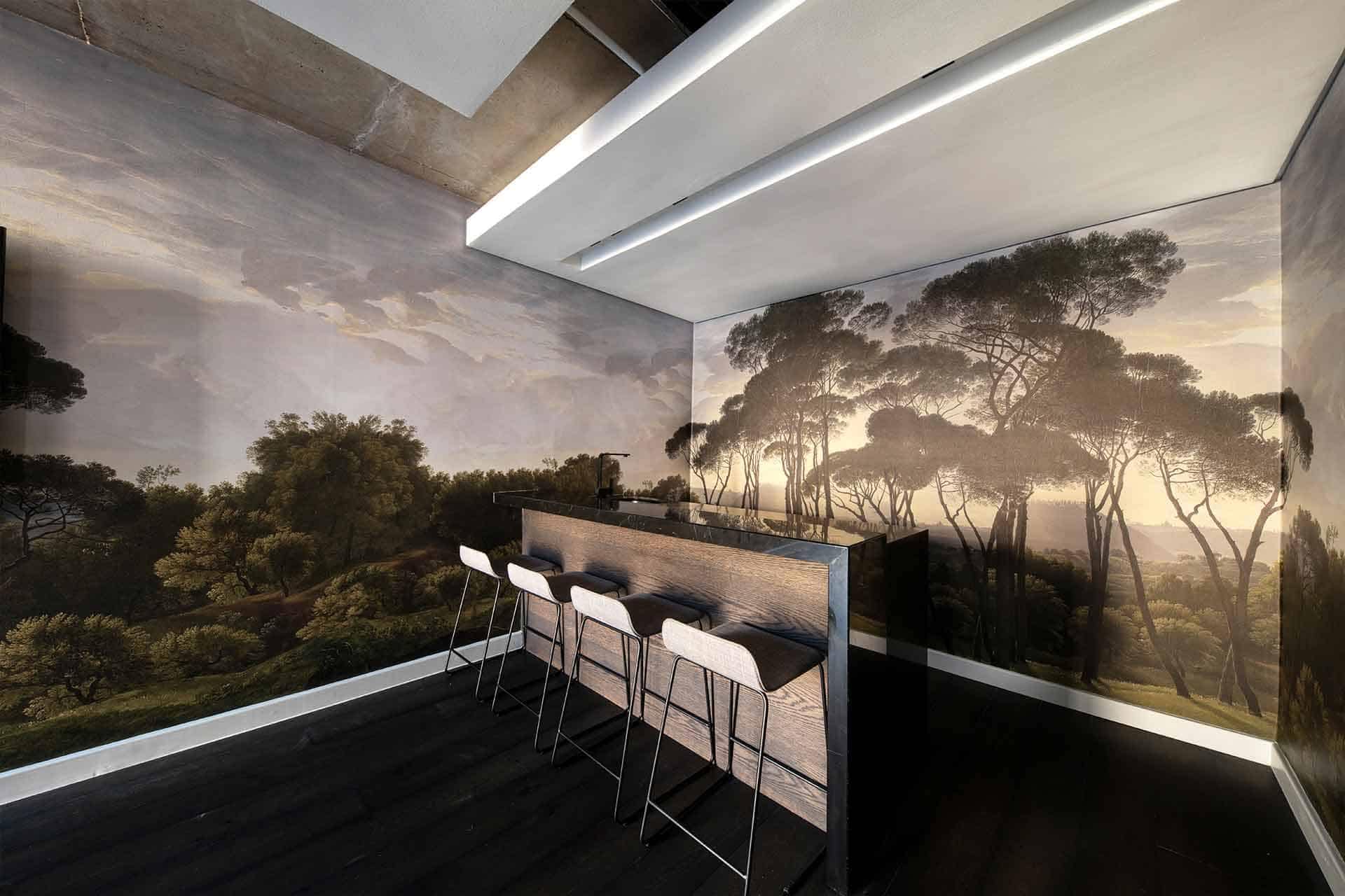 The wallpaper features a high-quality mural of a lush forest landscape. Elements include dense greenery, towering trees, and dappled sunlight filtering through the foliage. Colors range from deep emerald greens and mossy hues to sunlit yellows and earthy browns, creating a serene and natural ambiance. Perfect for adding an outdoor vibe indoors.