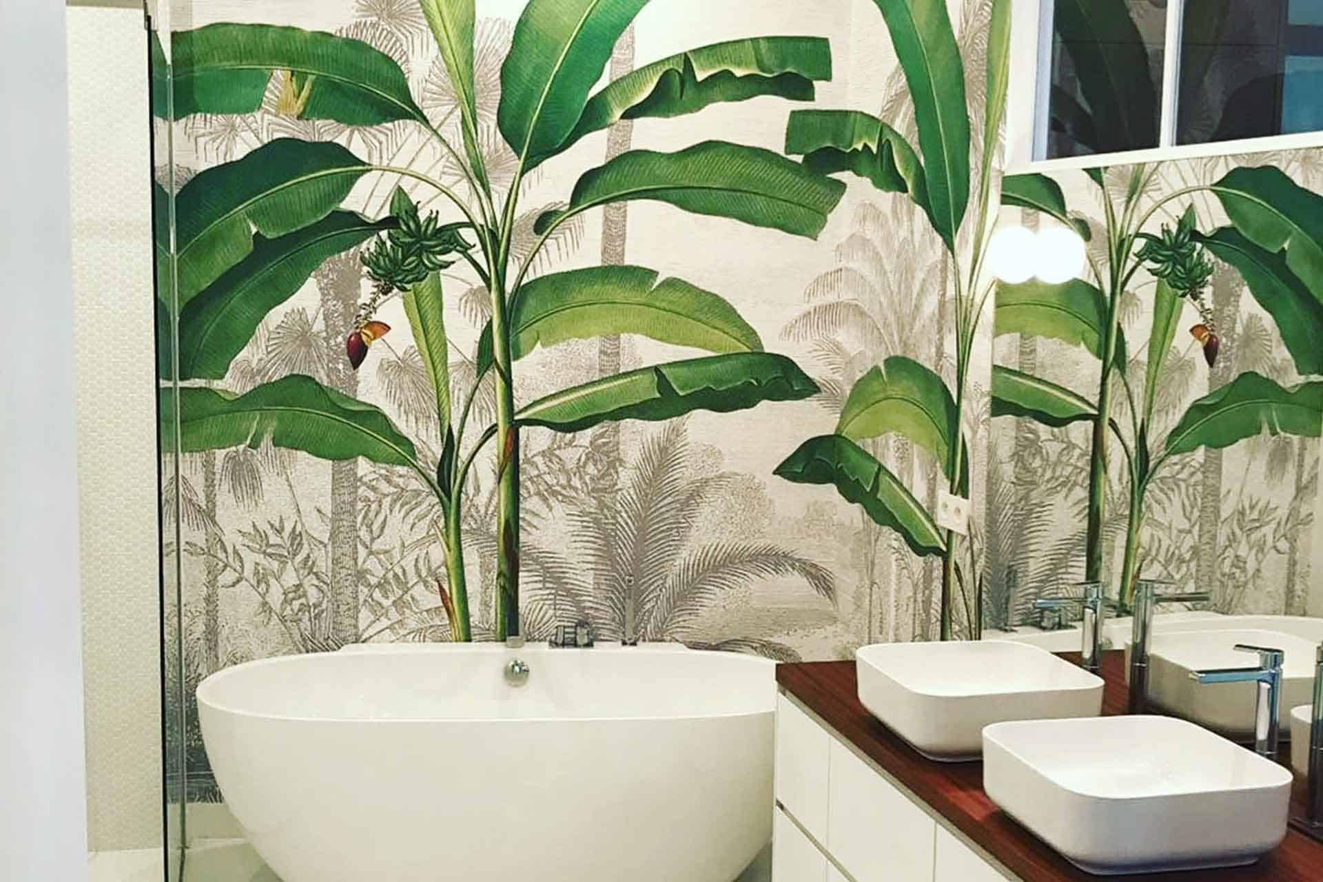 The bathroom features tropical-themed wallpaper behind the white bathtub, showcasing large green banana leaves. The wallpaper elements include lush greenery with varying shades of verdant green, creating a natural, vibrant backdrop. Perfect for enhancing your home's portfolio with its fresh and exotic ambiance.