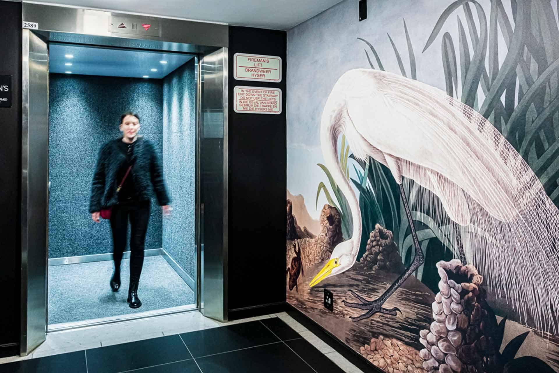 White heron mural, reeds, rocks, outdoor backdrop, detailed artwork. Vibrant colors: white heron, green reeds, gray rocks.