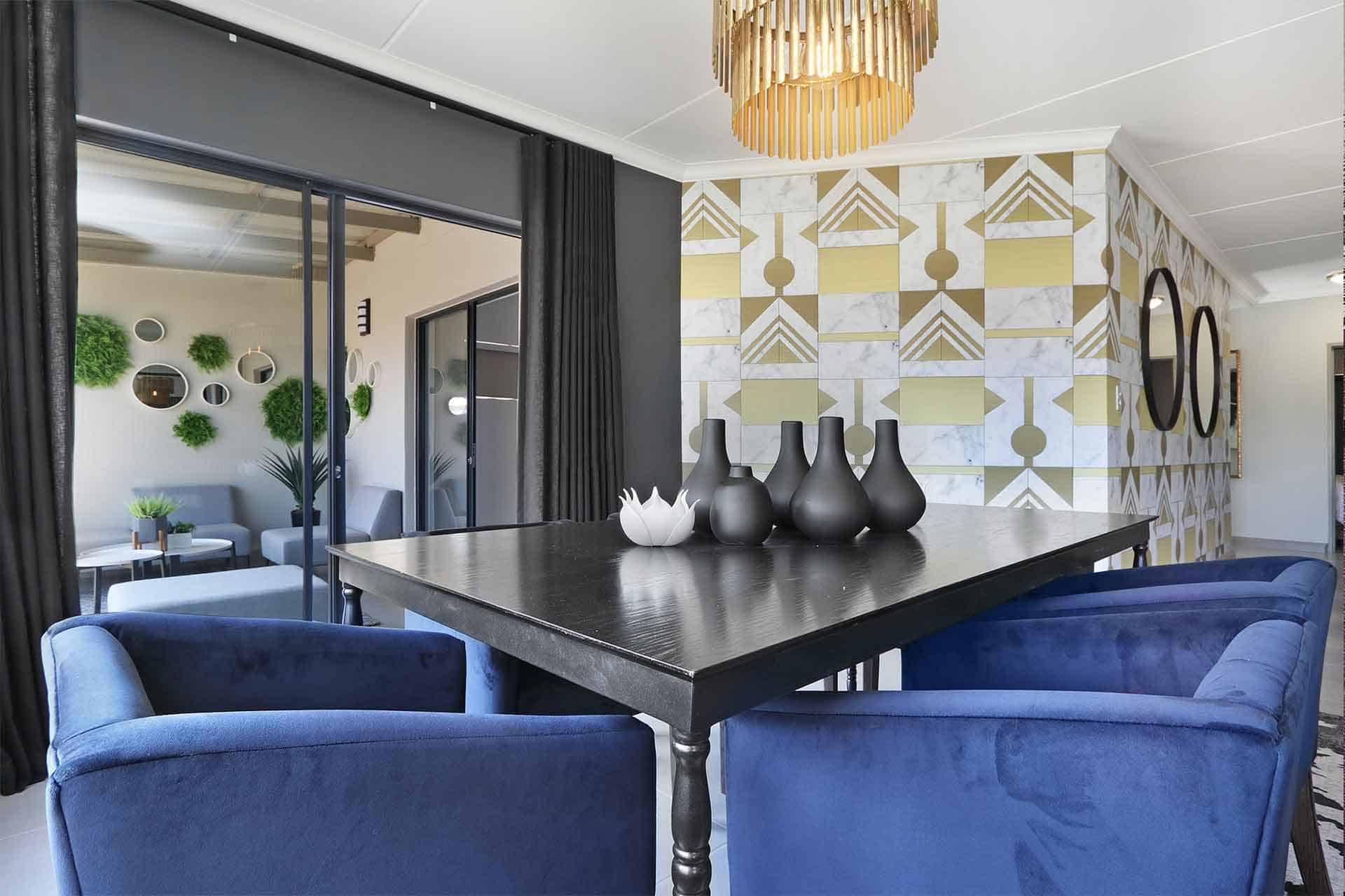 The geometric-patterned accent wall features a dynamic mix of bold shapes and lines in shades of navy, gold, and white. This striking design adds visual interest and sophistication to the dining area.