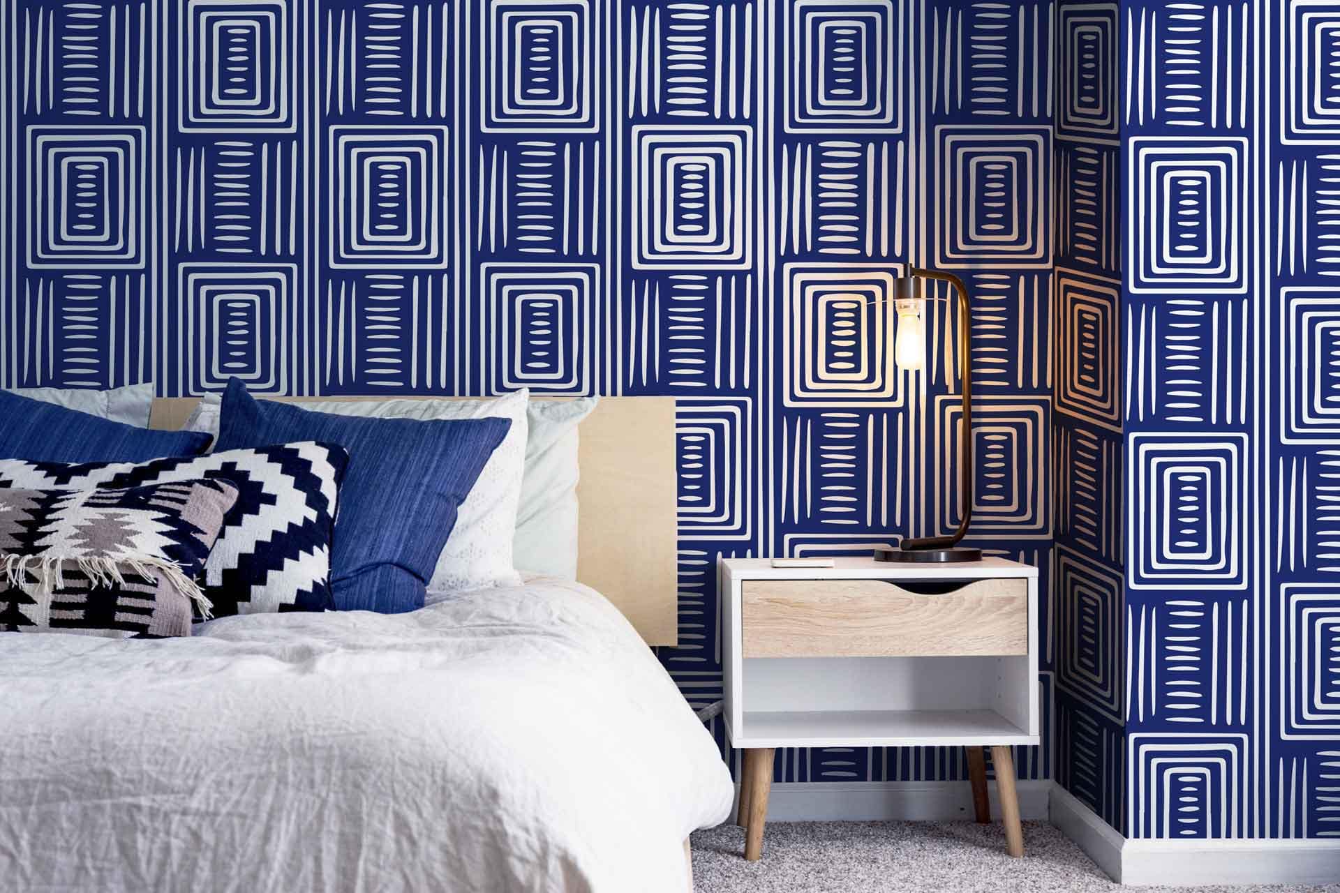 The bedroom features walls covered in blue geometric patterned wallpaper. The design includes a mix of deep navy and lighter azure tones, arranged in intricate, repetitive shapes that create a modern and stylish look. The geometric elements add depth and interest to the room's overall aesthetic.