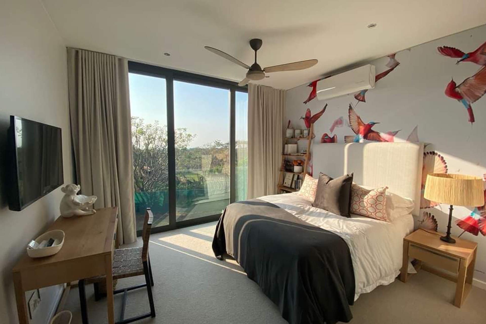 Bird-themed wallpaper with vibrant bluebirds, soft pastel-colored foliage, intricate branch patterns, and subtle green and yellow floral accents.