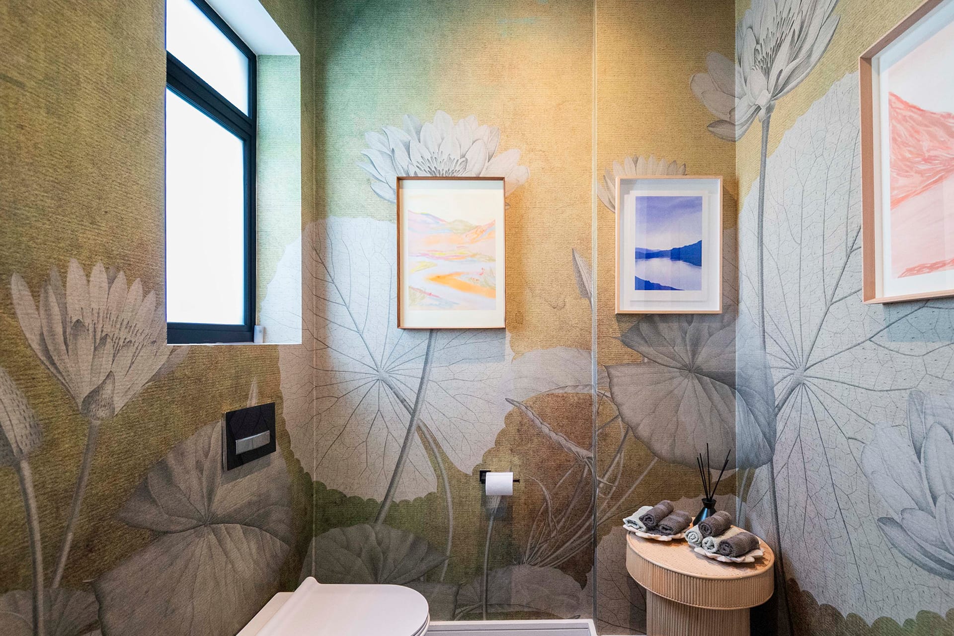 Large floral wallpaper covers the bathroom walls, featuring oversized blossoms in shades of pink, deep burgundy, cream, and soft green foliage. The design showcases richly detailed petals and leaves with subtle gold accents on a muted charcoal background. The flowers are lush and bold, giving the space a dramatic yet elegant feel.