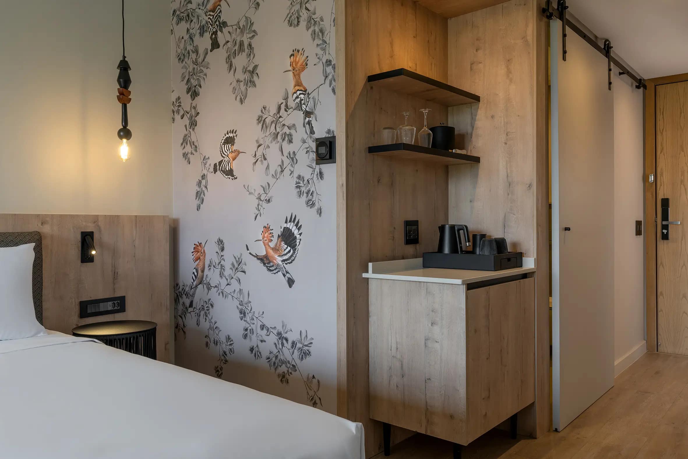 Bird-patterned wallpaper featuring delicate bird illustrations in soft hues and subtle natural tones, adding a whimsical and decorative touch to the hotel room’s design.