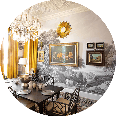The wallpaper is a detailed monochrome mural of a pastoral scene. The artwork is surrounded by framed paintings.