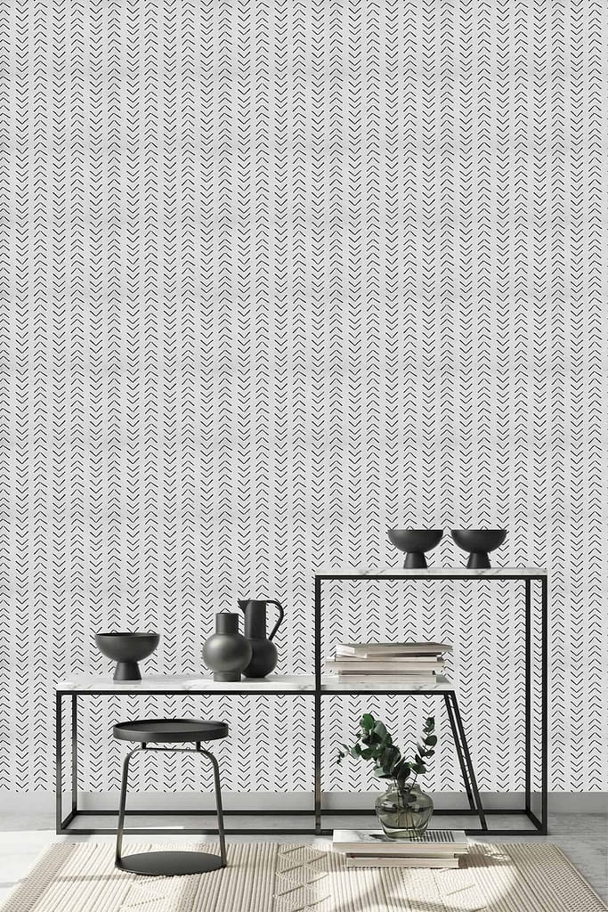 Chevron-patterned wallpaper features alternating zigzag stripes in black, white, and beige. The bold, geometric pattern adds visual interest and depth to the minimalist room.