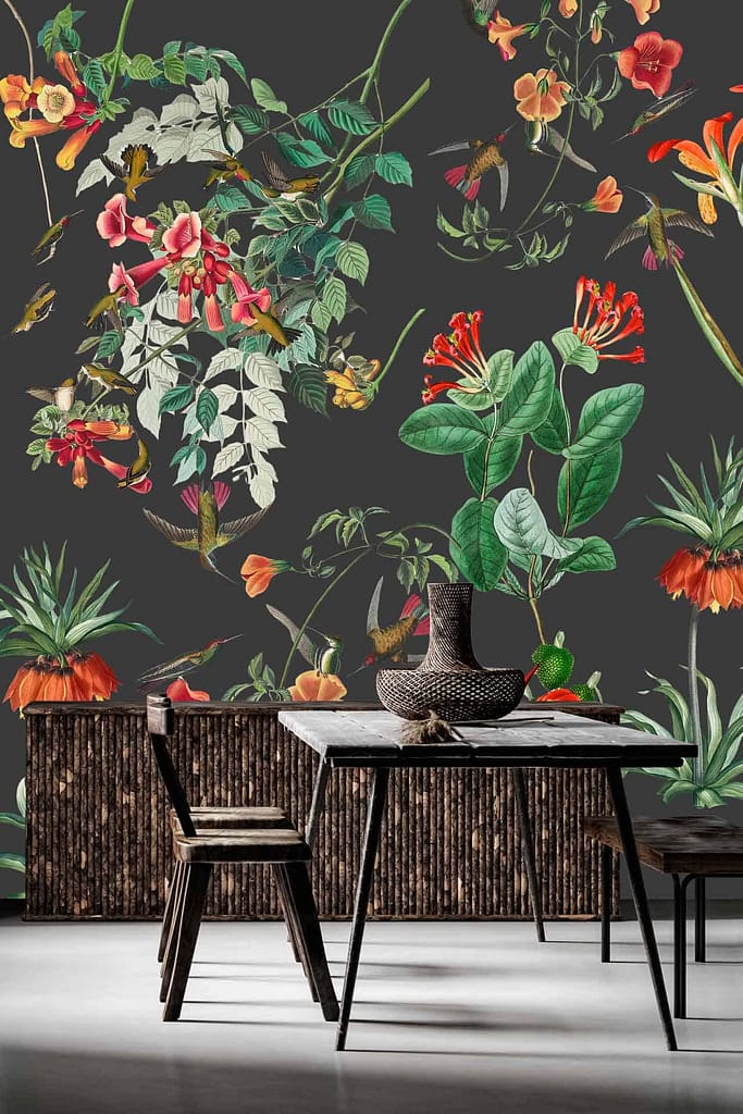 The wallpaper is a vibrant, botanical mural with various colorful flowers and leaves. It features lush greens, bright pinks, deep blues, sunny yellows, and rich reds. This lively design adds a burst of color and invigorates the atmosphere with its natural elements.