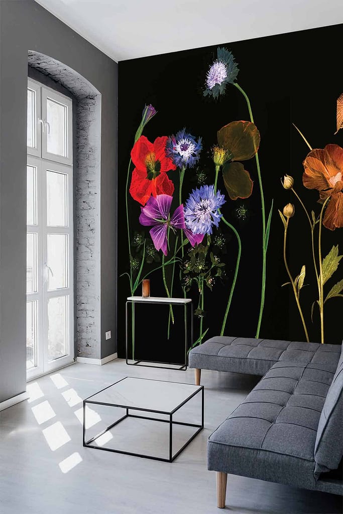 Dark floral wallpaper featuring vibrant, oversized flowers in rich hues like deep burgundy, emerald green, bold navy blue, and touches of gold. The wallpaper's intricate design showcases detailed petals and lush foliage set against a deep black background. Styled by Nomi.