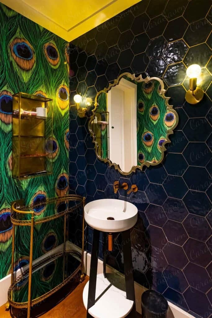 The bathroom boasts a striking accent wall featuring peacock feather patterned wallpaper. The design showcases vibrant teal, turquoise, and gold hues with intricate feather details.