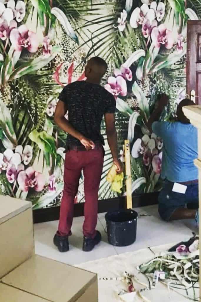 Floral and leafy wallpaper featuring vibrant greens, soft pastels, delicate blossoms, and lush foliage.