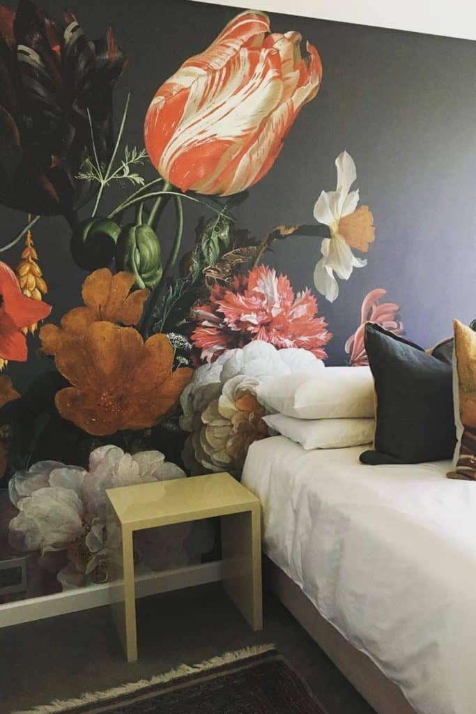 Floral mural wallpaper featuring large, colorful flowers including red blooms, orange petals, and white flowers. The design highlights vibrant botanical artistry with bold, vivid colors.