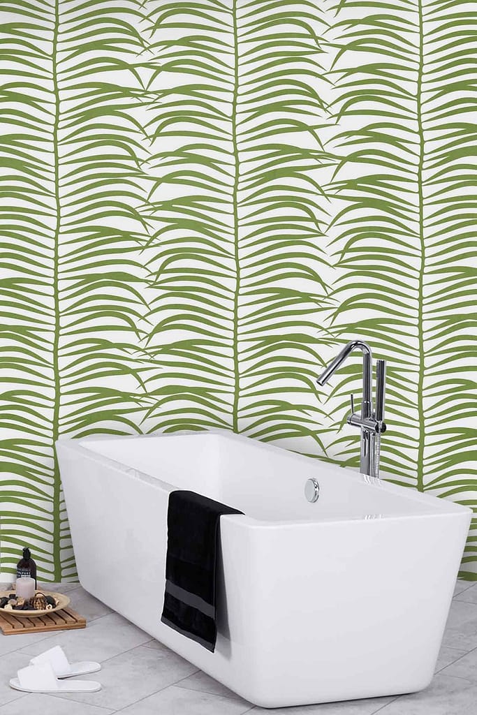 The wallpaper behind the freestanding white bathtub showcases a striking green leaf pattern, evoking a lush, fantastical atmosphere. The design consists of varying shades of green leaves on a soft background, adding depth and vibrancy to the space. This captivating wallpaper is an essential element in creating a serene and inviting bathroom ambiance.