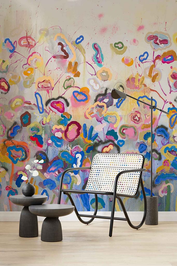 The wallpaper in this modern living space features a vibrant, abstract floral mural, displaying a dynamic array of colors such as bold reds, vivid blues, lively greens, and striking yellows. The design evokes the fluidity and grace of an elegant dance performance with its swirling patterns and intricate details.