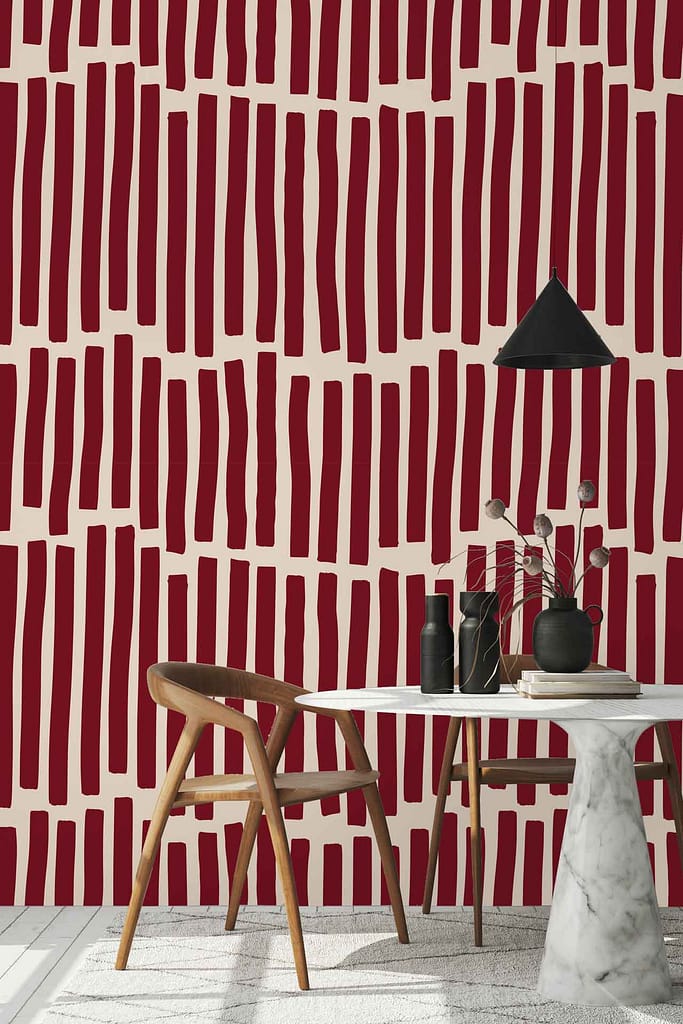 The modern dining area is brought to life with the captivating wallpaper from the Fabrication collection. Dominating the space, this wallpaper features vertical, irregular stripes in a rich dark red that dramatically contrast against a light beige background. The deep tones of red create a sense of vibrancy and warmth while the beige base evokes an airy openness, balancing the intensity. The uniquely non-uniform lines add depth and texture, making each stripe appear as if it tells its own story. This dynamic backdrop enhances every element in the room by adding an artistic touch through its bold yet refined color palette and distinctive patterning.