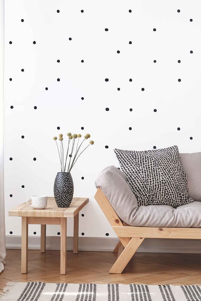 White wallpaper with a bold black polka dot pattern, creating a striking and modern visual effect. The contrasting black circles on the white background make the wall stand out as the focal point of the room.