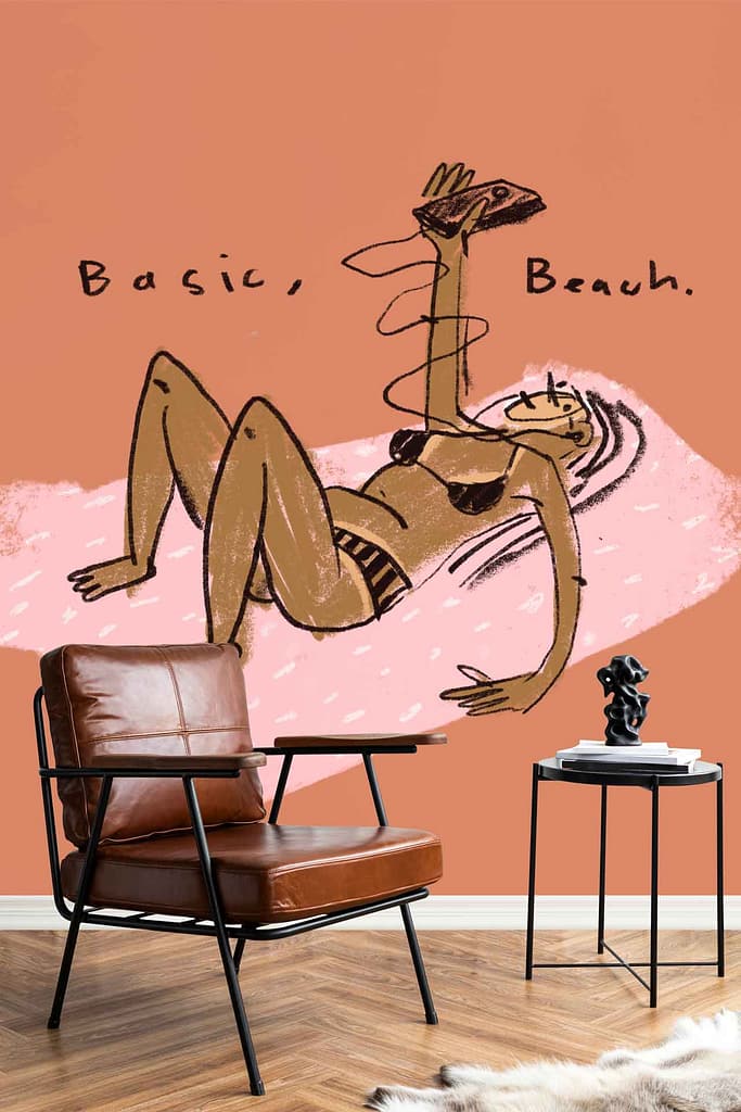 Wallpaper mural shows a woman in a bikini lying on her back, holding a phone, with the phrase “Basic, Beach.” above her. The design features warm skin tones, bold black outlines, and pastel colors against a light background.
