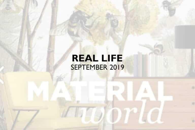 **Magazine Cover Description:**

*Center Text:* REAL LIFE SEPTEMBER 2019

*Below Center Text:* MATERIAL world

*Background:*
- **Wallpaper Elements:** 
  - Bees on flowers
  - The pattern includes chairs.
- **Colors:**
  - Light-colored room
  - Wooden tones from the dresser and lamp