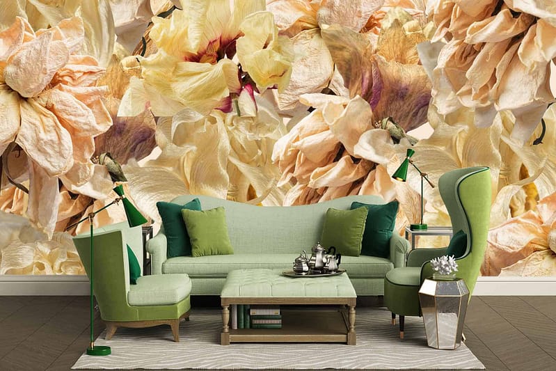 The wallpaper in the modern living room highlights a large floral mural with intricate details. Colors featured prominently in the mural include shades of beige, cream, and light yellow. The floral design showcases delicate petals and leaves, creating an elegant backdrop that complements the green furniture in the space.