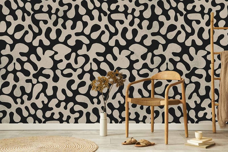 The wallpaper features a bold abstract black and tan pattern, reminiscent of historical art. It includes sharp lines, intricate curves, and dynamic shapes. The primary colors in the wallpaper are deep black and rich tan, creating a striking contrast that draws attention. The pattern is elaborate yet balanced, making it both eye-catching and harmonious within the room's decor.