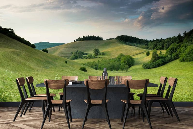 The wallpaper displays rolling green hills under a partly cloudy sky, creating an illusion of the outdoors with lush landscapes. Key elements include vibrant green tones, soft blue sky segments, and wisps of white clouds.