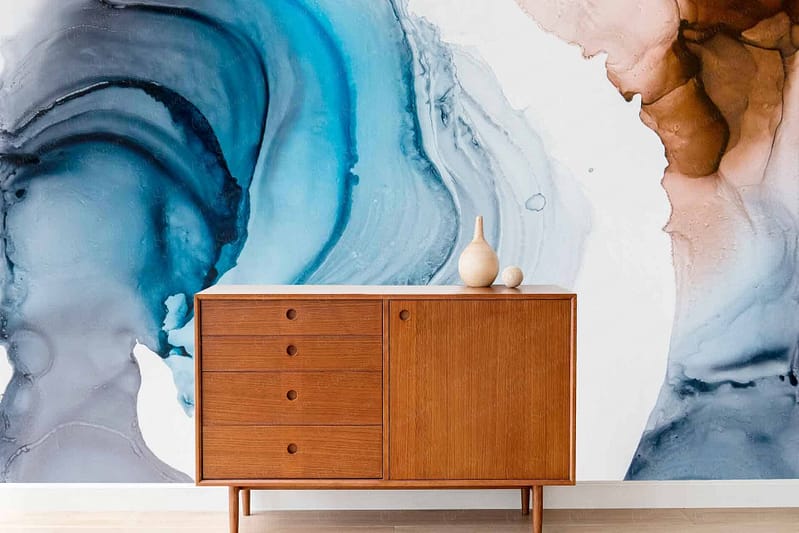 A vibrant, abstract watercolor mural showcases swirling shades of blue, white, and brown. The pattern appears to be in motion, creating a dynamic backdrop with fluid, intertwined colors.