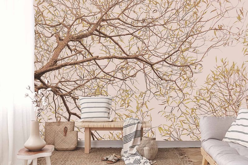 The wallpaper showcases a stunning, serene mural of a tree with intricate branches and foliage. The hues range from warm browns and lush greens to soft golden tones, encapsulating the tranquility of nature. This vibrant depiction serves as an elegant backdrop, bringing the essence of an outdoor sanctuary into the cozy room.