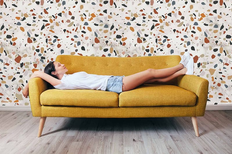 Terrazzo-patterned wallpaper with multicolored specks. The design includes colors like white, blue, pink, and gray that harmonize with the stylish flooring.