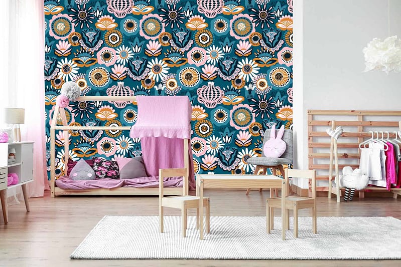 The wallpaper in Annabella's children’s playroom features vibrant, colorful floral patterns. It includes a mix of pink roses, yellow daisies, bluebell clusters, green leafy vines, and orange tulips on a light pastel background.