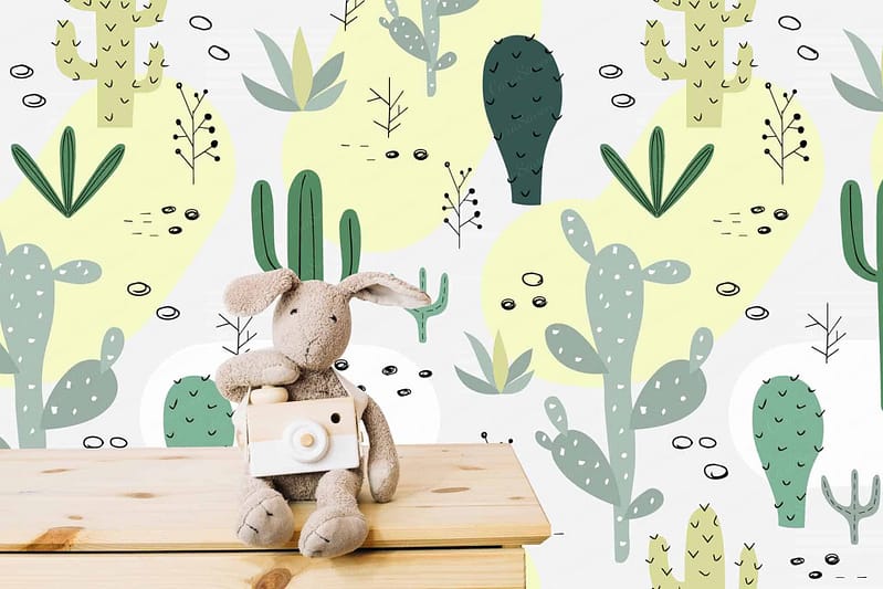 The wallpaper features whimsical, Arizona-inspired designs with a variety of cactus illustrations and doodles. It includes various shades of green and yellow. Cactus types depicted range from tall saguaro cacti to round barrel cacti. The playful patterns create a vibrant and lively backdrop, capturing the essence of the desert landscape.
