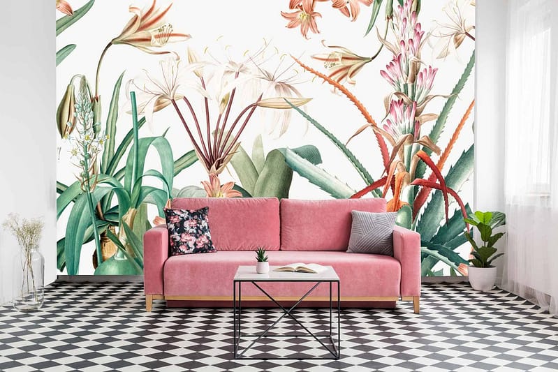 The wallpaper in the Chelsea living room features a vibrant floral mural with large, colorful flowers and lush green leaves. The flowers display a variety of rich hues, including reds, pinks, yellows, and blues. The green leaves add depth and natural contrast against the bright blossoms. This striking mural serves as an eye-catching backdrop to the space.