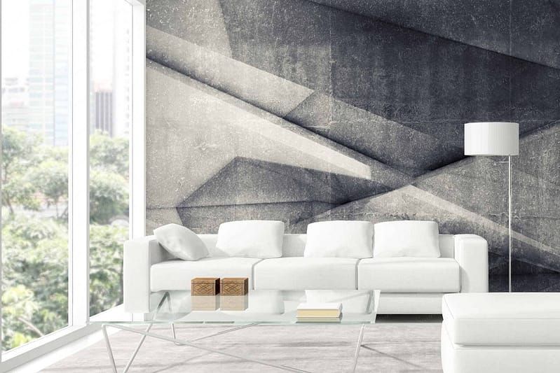 Geometric accent wall features interlocking shapes in varying shades of grey, including light grey, charcoal, and slate. The pattern combines sharp angles and clean lines, creating a modern, dynamic visual effect. Elements like triangles, hexagons, and parallelograms are prevalent. Key colors: light grey (#d3d3d3), charcoal (#36454f), slate (#708090).