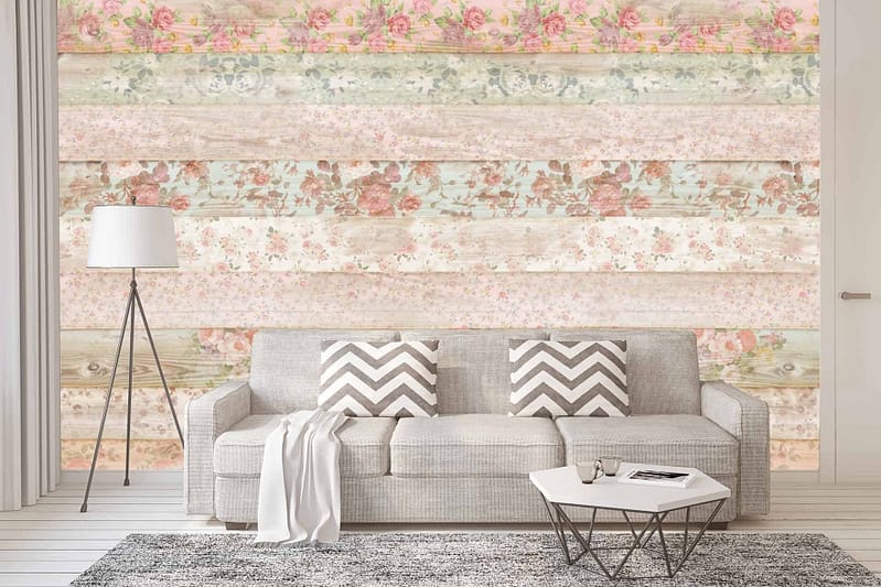 The wallpaper features a colorful, floral-patterned wooden plank design. It includes vibrant hues like pink, yellow, turquoise, and green, intermingled with delicate flower motifs. This eclectic arrangement exudes a coastal charm reminiscent of the English Channel's whimsical decor. The planks are arranged vertically with visible grain textures contributing to the rustic yet lively ambiance of the room.